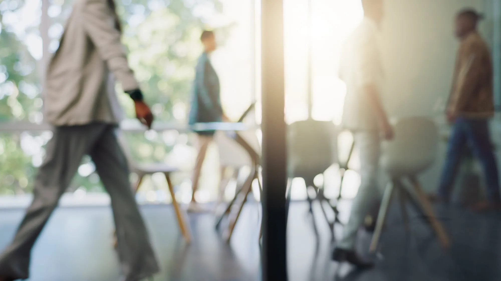 Menschen gehen durch ein helles Büro, im Gegenlicht unscharf